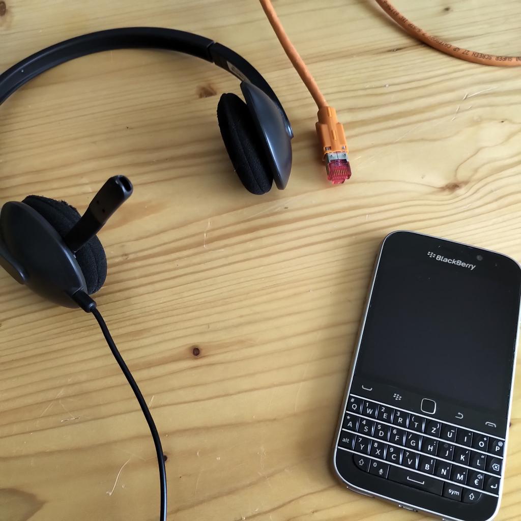 Ein Blackberry-Smartphone und ein Headset auf einer hölzernen Tischplatte